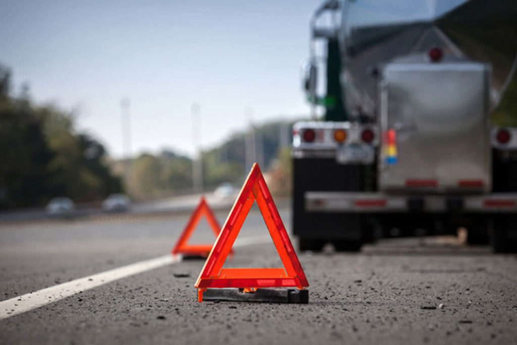 Hazard signs on roadside beside tractor tailer